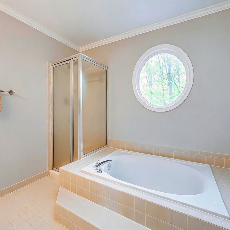 The soaking tub and walk-in shower, with a round window above