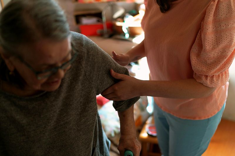 A caregiver supporting an older adult while walking
