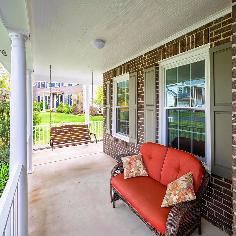The covered front porch with a wicker sofa and bench seating, looking over the front garden